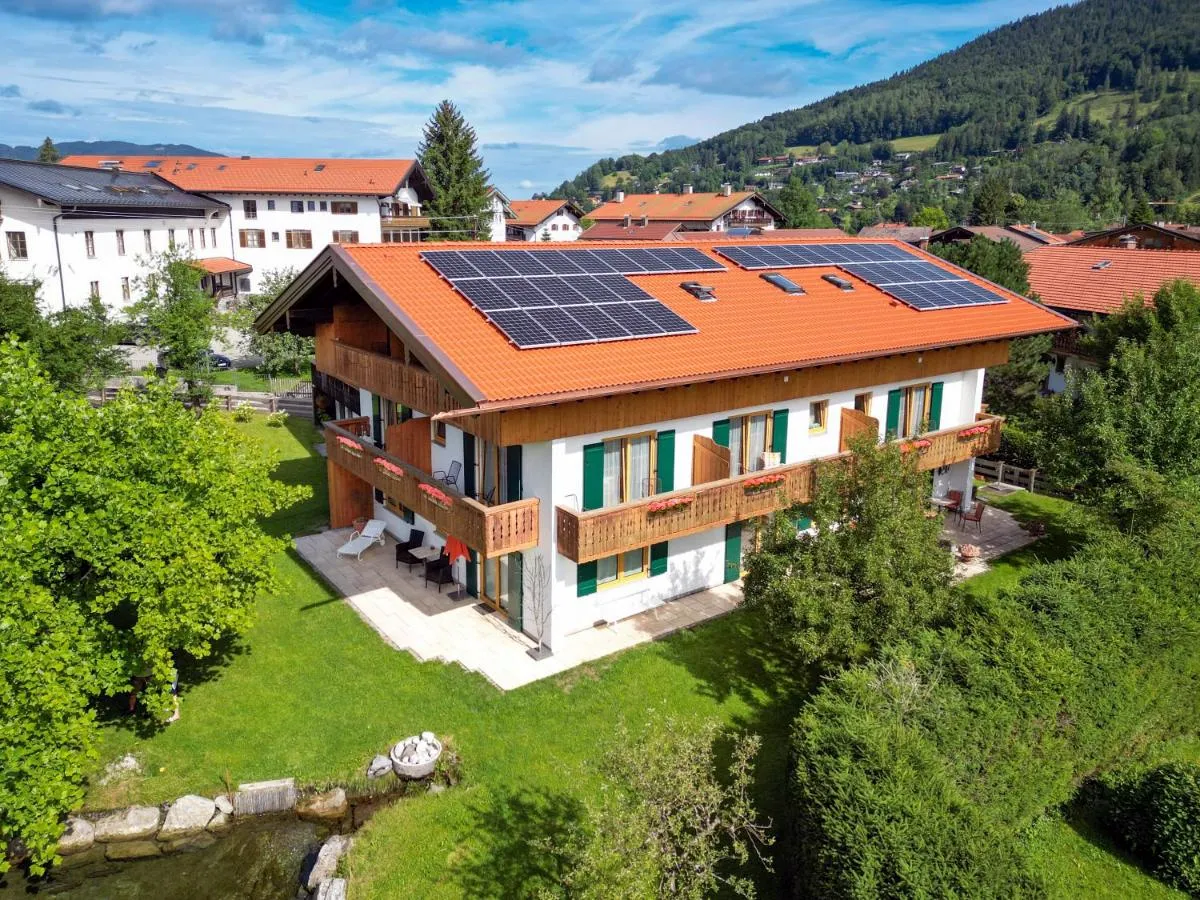 Das Gästehaus mit grünen Fensterläden und Holzbalkonen im Garten, Luftbild