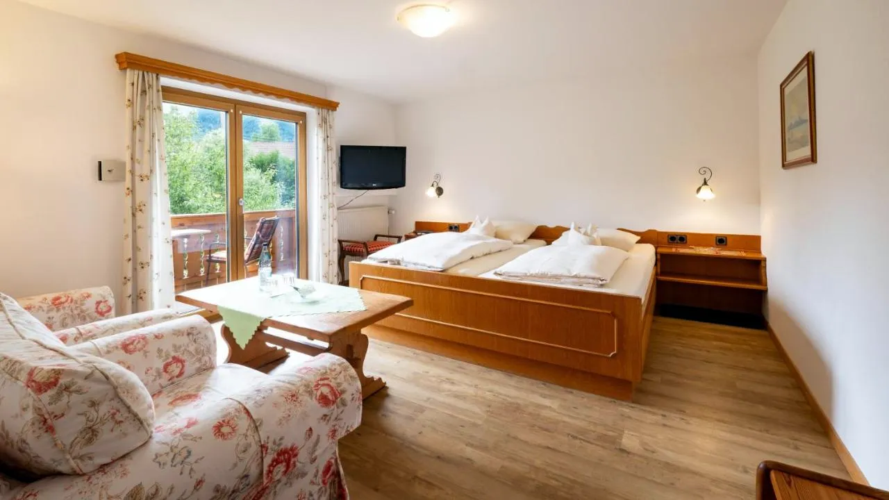 Doppelzimmer mit Holzbett, Blümchensessel und Balkontür