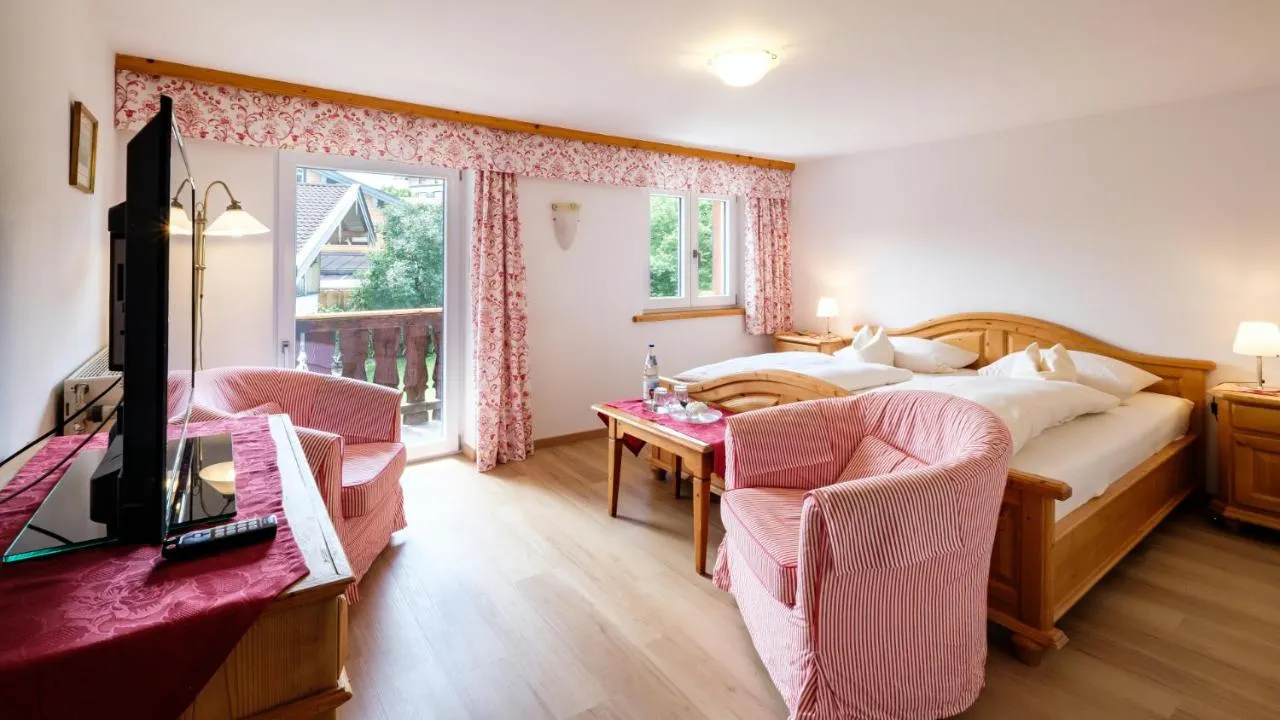 Zimmer mit Balkon, rosa Sesseln und Holzbett